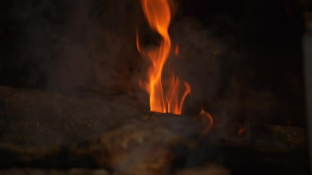 Closeup bright warm glowing smoking flames from log burning fire slow motion