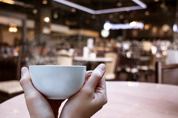 hot cup in hand at coffee shop background