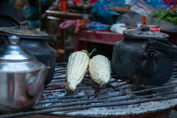 Corn cobs and tea kettles being heated on charcoal grill at a market in northern Vietnam in winter