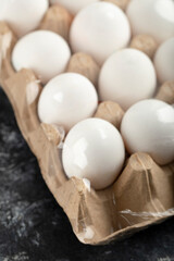 Raw chicken eggs in egg box on a marble background
