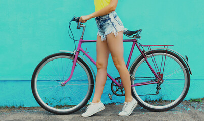 Close up of beautiful woman model in shorts with bicycle posing on a blue background