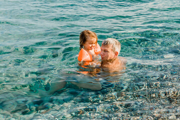 Grandfather and toddler girl having fun in sea