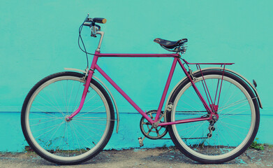 Fototapeta na wymiar Retro pink bicycle standing in the city on a blue background