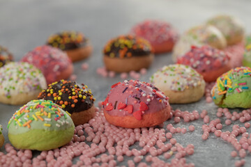 Fototapeta na wymiar Colorful sweet small doughnuts with sprinkles and a cup of tea