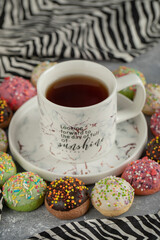 Colorful sweet small doughnuts with sprinkles and a cup of tea