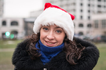 Portrait of a beautiful girl in a santa claus hat on a city