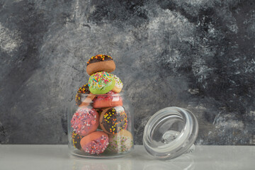 A glass jar full of small colorful doughnuts