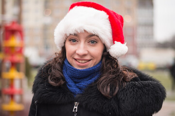 Portrait of a beautiful girl in a santa claus hat on a city