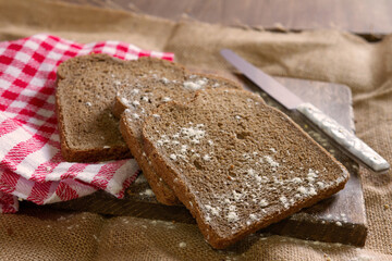 rye bread on rustic wood and rustic fabric and red boxed tablecloth and knife