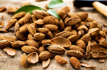 gruppe geöffneter und ungeöffneter Mandeln mit hammer auf einem leinentuch