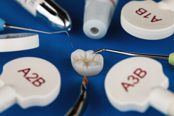 composition of high quality dental crown inlay, with beautifully laid out instruments and composites on a blue background