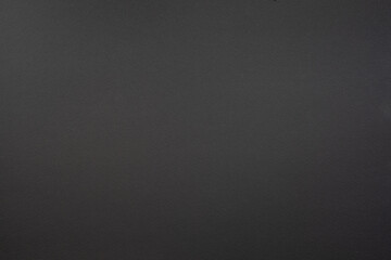 Black cardboard background with closeup on a piece of black colored paper.