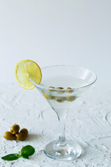 margarita cocktail in the bar. martini glass of cocktail with green mint and olives on white background. Glasses for martini with lemon on the table. copy space. vertical. alcohol drinks. top view