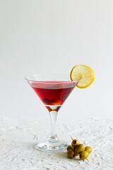 cosmopolitan cocktail in the bar. martini glass of red cocktail with olives and lemon on white background. Glasses for martini on the table. copy space. alcohol drinks. vertical