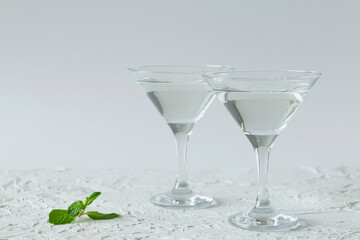 two martini glasses of cocktail with green mint on white background. alcohol drinks. Glasses for cocktail on the table. copy space