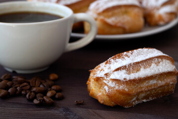 Traditional french tasty dessert on dark background. homemade vanilla eclairs or profiteroles on a wooden table. copy space. cup of black coffee with beans.