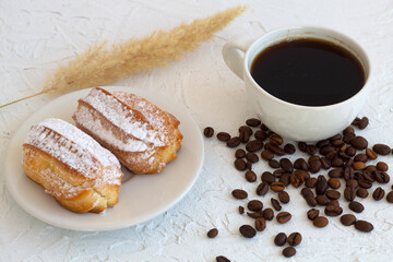 Plate with eclairs on a table. coffee cup with coffee beans on white background. Traditional french tasty dessert. top view