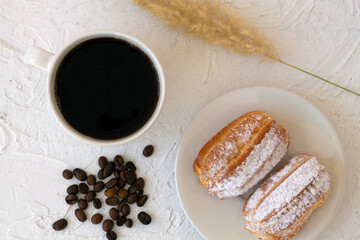 Traditional french eclairs on a plate on table. coffee cup with coffee beans on white background. tasty dessert. top view