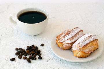 Traditional french eclairs on a plate on table. coffee cup with coffee beans on white background. tasty dessert.