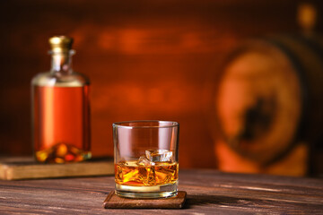 Glass of whiskey with ice on wooden table