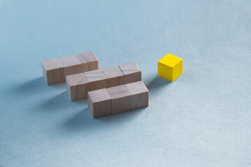 Top view of wooden blocks on blue, one yellow cube. leadership concept