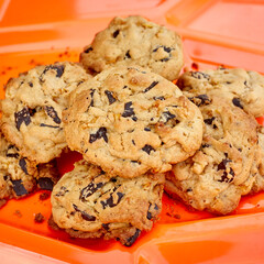 Group of Chocolate Chip Cookies on Plastic Orange Platter, Square Crop