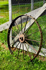 Fototapeta na wymiar Single Rusty Old Wagon Wheel Leaning on Fence