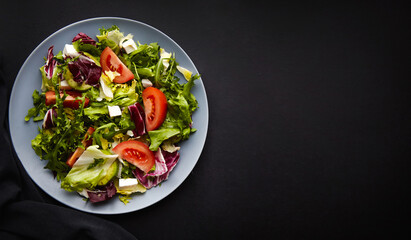 Mix salad with tomatoes, feta, lettuce, spinach. Top view with text space