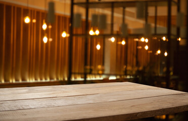 empty wooden table on blurred light gold bokeh of cafe restaurant on dark background, blurred cafe interior place for your products on the table