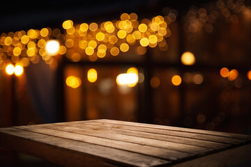 empty wooden table on blurred light gold bokeh of cafe restaurant on dark background, place for your products on the table