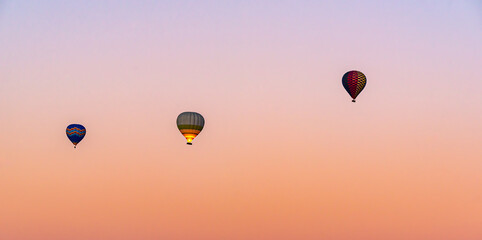 Hot air balloon flying over Cappadocia, pink sky