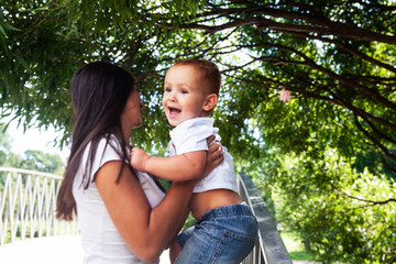 Fototapeta premium young pretty brunette mother with little cute boy walking in park happy smiling, lifestyle people concept