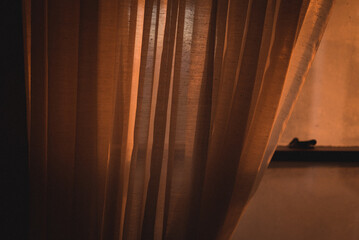 A window mostly covered by a curtain at sunset