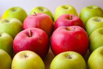 Green and red apples stand on a wooden surface