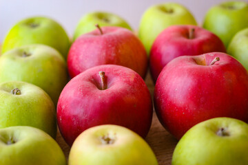 Green and red apples stand on a wooden surface