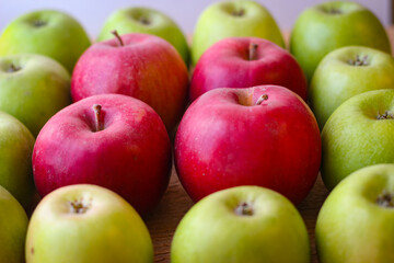 Green and red apples stand on a wooden surface