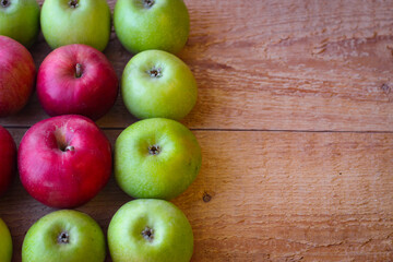 Green and red apples stand on a wooden surface