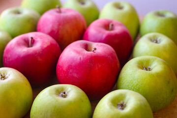 Green and red apples stand on a wooden surface