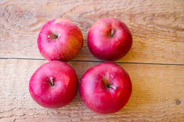 Red apples stand on a wooden surface