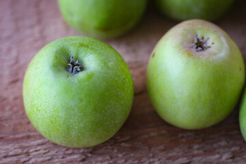 Green apples stand on a wooden surface