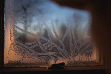 Lines of frost on a window at sunset
