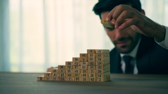Businessman building tower of wooden blocks on office table working together on company strategy plan development, helping, searching new effective solutions concept.