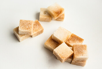 Reed sugar in the form of cubes lies on a white background with a handful