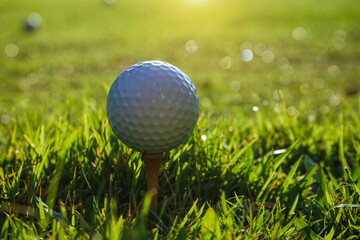 Golf ball on tee ready to play.Golf ball on a green lawn in a beautiful golf course with morning sunshine.