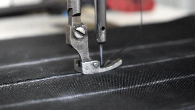 Sewing needle stiching edges of raw cloth material