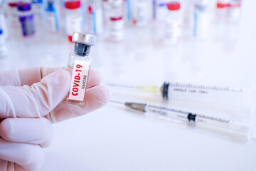 Doctor hand in medical glove hold bottle of Coronavirus vaccine bottle , Vaccination and immunization to protect patient from flu ,disease and covid-19  ,selective focus