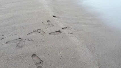 Fototapeta na wymiar Man footprint on beach shore sand