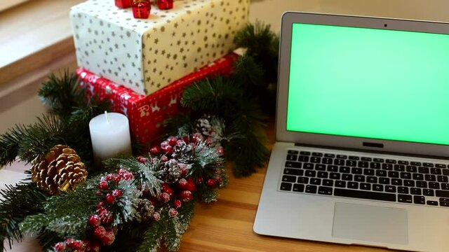 Closeup of green screen laptop with New Year presents on background. Winter holidays. Connect with friends. Chroma key notebook. Free content. Mock-up monitor. Online greeting. Internet surfing. 