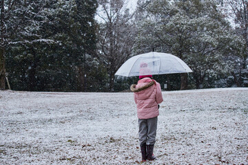 雪が降っている公園で散歩している可愛い女の子の子供