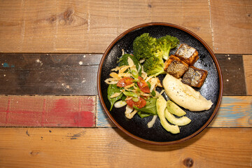 A delicious plate of Salmon and salad on a wooden kitchen work top